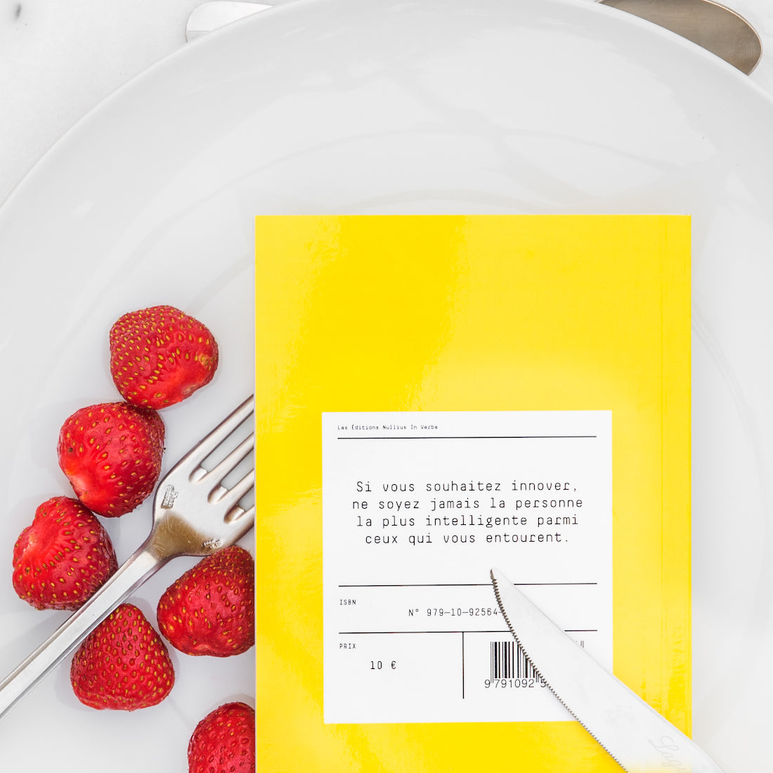 Le livre est retourné dans l'assiette avec des fraises. On peut lire la quatrième de couverture.