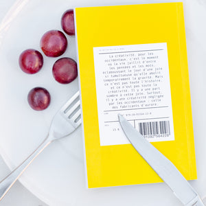 Le livre est retourné dans l'assiette avec des grains de raisins. On peut lire la quatrième de couverture.